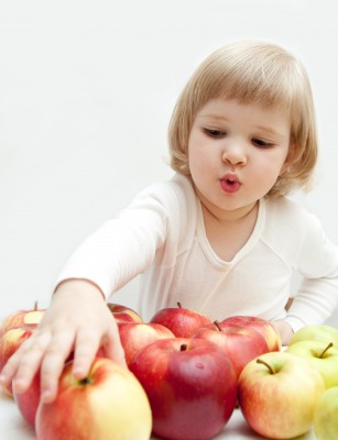 niña rubia cogiendo una manzana