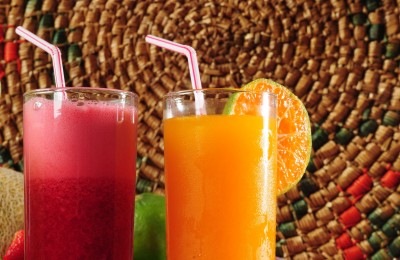 zumos de fresa y naranja sobre fondo tropical